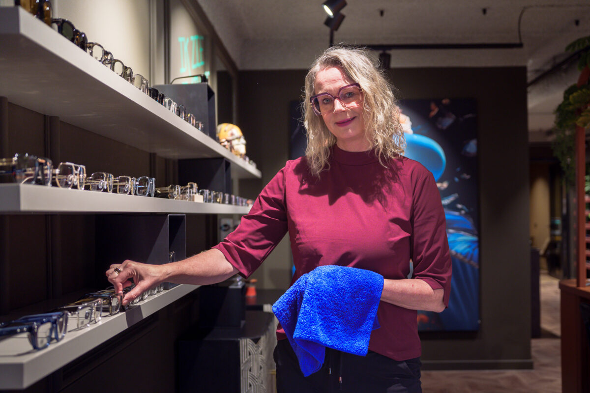 Medewerker poetst een bril op bij de display