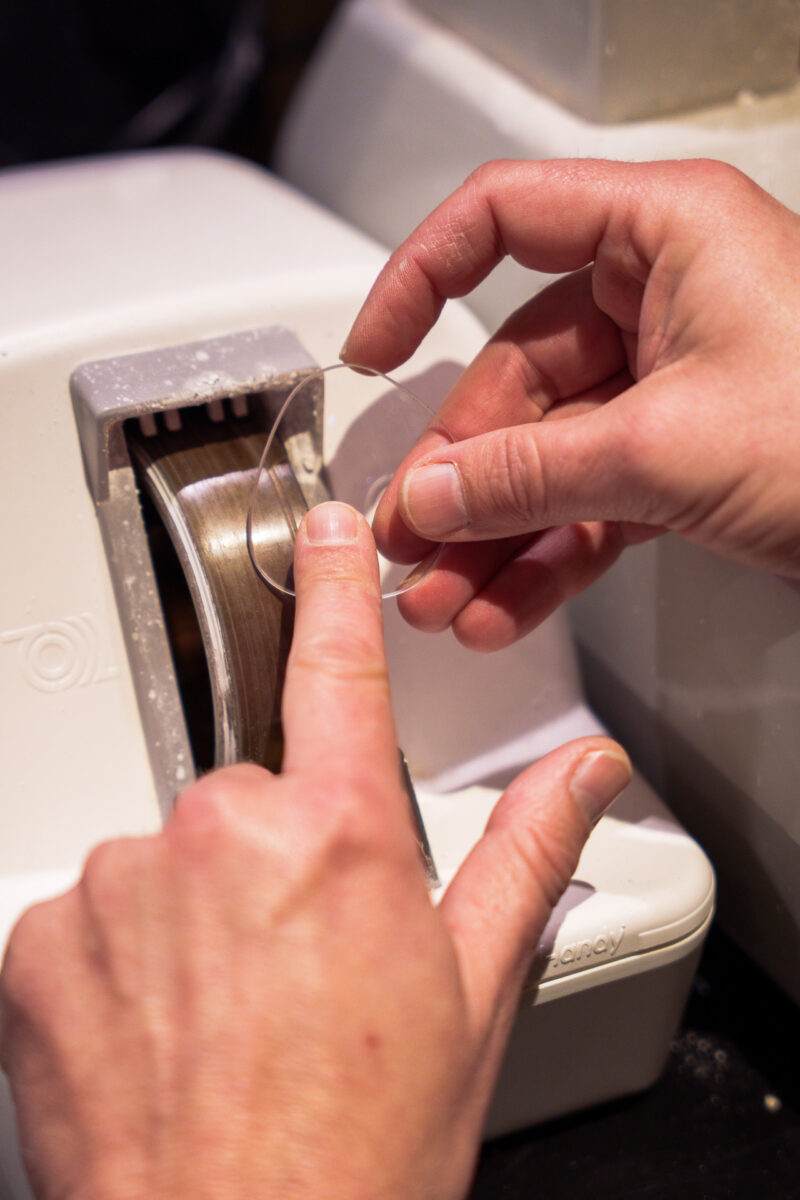 Opticien slijpt een brillenglas op de Handy edger